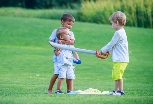 Two Older Boys Fighting With Toddler Boy And Threatening Him With Toy Sword