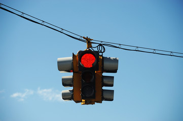 red traffic light hanging against sky