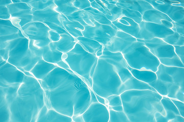 Water surface in swimming pool with sun reflection