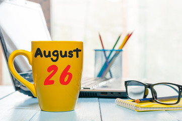 August 26th. Day 26 of month, calendar on cappuccino yellow cup at traveller workplace background. Summer time. Empty space for text