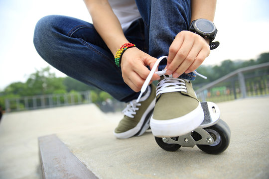 freeline skateboarder tying shoelace at skatepark ramp