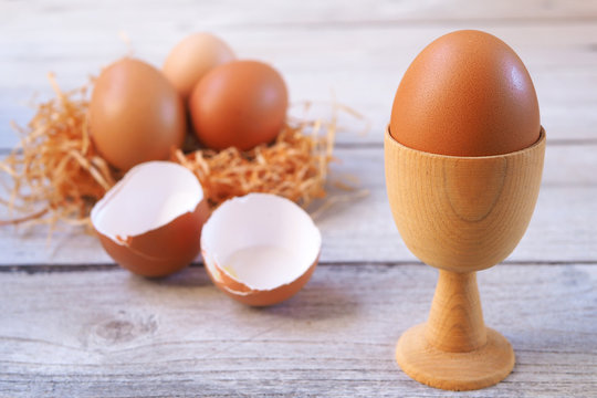 Close up of egg in a wooden holder on a wooden table. Selective focus.