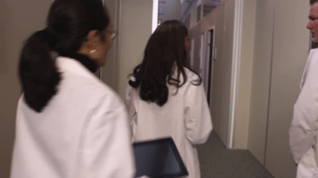 A group of doctors stand in the hallway and discuss an important matter