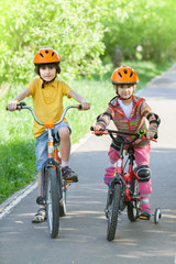 A little girl and boy in helmet riding a Bicycle