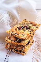 A stack of healthy crispy cereal bar or muesli bar with pumpkin seeds, sunflower seed, sesame, nuts and dried fruits with honey.