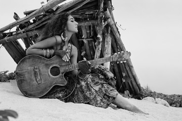 Atrractive young hippie woman with guitar outdoors