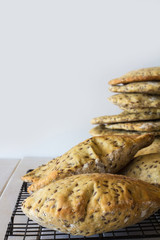 Wholemeal Pita Bread with Seeds Stacked on Cooling Rack on White Wooden Table with Copy Space Selective Focus Vertical