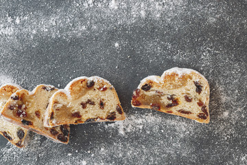 Sliced Christmas stollen with icing sugar. Top view, vintage toned image, blank space.