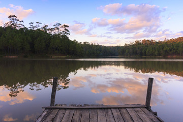 Beautiful natural view of serene lake in sunset with a wooden dock beside the lake.