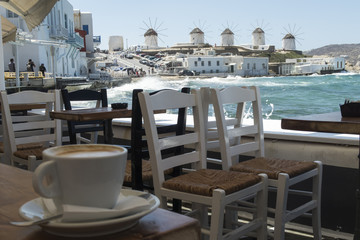 Mykonos, Greece - August 14 2016: Coffee with a view of the windmills. The windmills were used to mill wheat in the past. Now they only stand as an attraction.