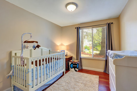 Cozy nursery room with white wooden crib.