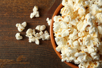Popcorn in bowl on wooden brown background