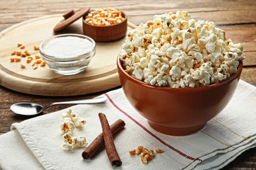 Popcorn in bowl on wooden brown background