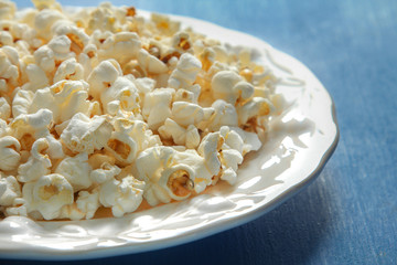 Popcorn in plate on blue wooden table