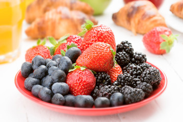 ripe berries and croissants on wood, selective focus