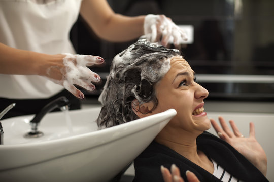 scared young woman in a hair salon while washing her hair