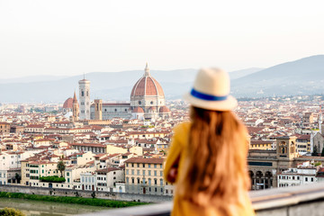 Young female tourist looking on the old town of Florence from Michelangelo square in the morning in Italy. Back focus - obrazy, fototapety, plakaty
