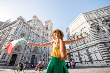 Outdoor kussens Young smiling female traveler standing with italian flag in front of the famous Santa Maria del Fiore cathedral in Florence. Promoting tourism in Italy © rh2010