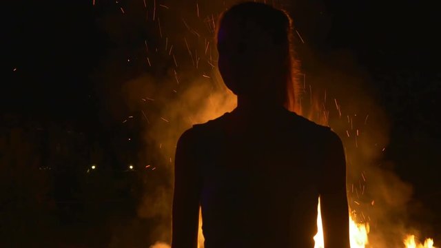 Silhouette of a young woman on in front of fire
