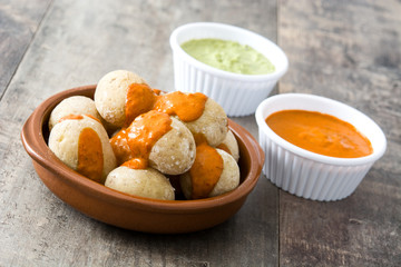Canarian potatoes (papas arrugadas) with mojo sauce on wooden table

