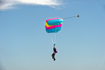 Paraglider flying on colorful parachute in blue clear sky at a bright sunny summer day. Active lifestyle, extreme hobbies
