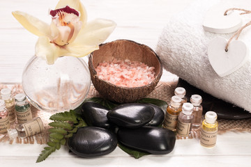 spa concept with stones, flowers , essential oils and mineral salt  on wooden table