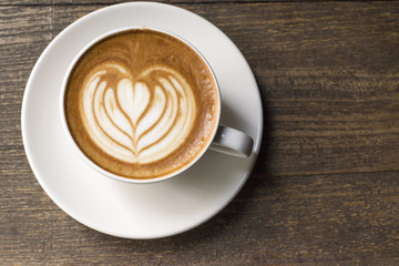 "Latte art" hot coffee on dark grained wood table from above