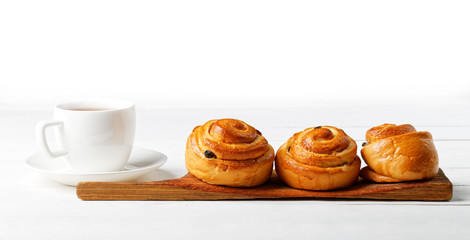 Raisin Buns and cup of tea on white table