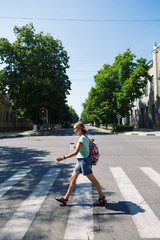 Side view of young hipster woman with cup of coffee to go walking along zebra crossing