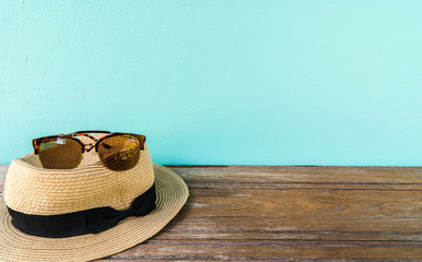 sunglasses and straw hat on wooden table with vintage cement wal
