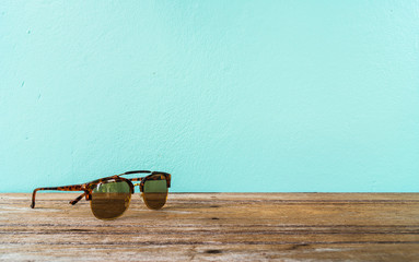 sunglasses on wooden table with vintage cement wall background