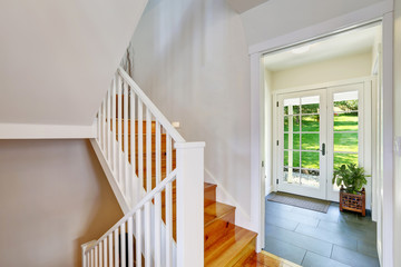 Bright white hallway interior with wooden staircase