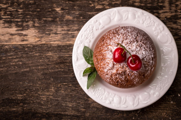 Tasty muffin with cherry and mint on vintage wooden background