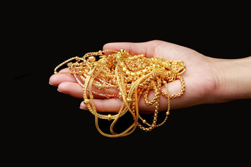 Hand holding group of gold jewelry isolate on black