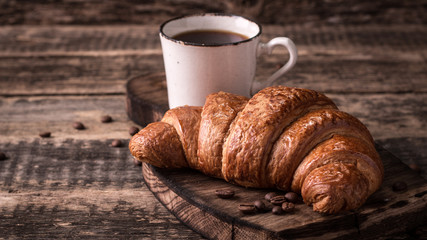 Breakfast with coffee and croissants on wooden vintage table