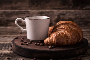 Breakfast with coffee and croissants on wooden vintage table