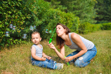 Mother with her son blowing bubbles at summer day