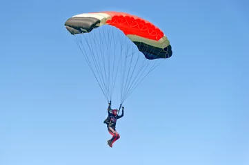 Fototapeten Gleitschirmfliegen auf buntem Fallschirm im blauen klaren Himmel an einem sonnigen Sommertag. Aktiver Lebensstil, extreme Hobbys © sergbob
