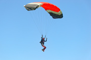 Paraglider flying on colorful parachute in blue clear sky at a bright sunny summer day. Active lifestyle, extreme hobbies