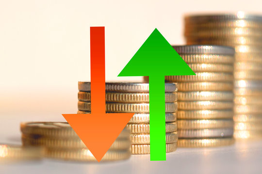 Red and green arrow on the background of coins . The concept of reduction and revenue growth