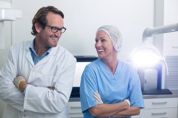 Smiling dentist and dental assistant standing with arms crossed