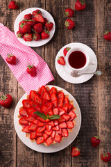 Tart with strawberries and whipped cream on wooden vintage table