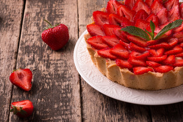 Tart with strawberries and whipped cream on wooden vintage table