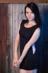 Fototapeta premium Beautiful girl in evening dress, the model poses against a wooden wall,