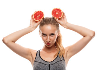 Beautiful sportive girl posing, holding grapefruit over white background.