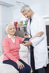 Obraz premium Doctor Checking Blood Pressure Of Senior Patient In Rehab Center