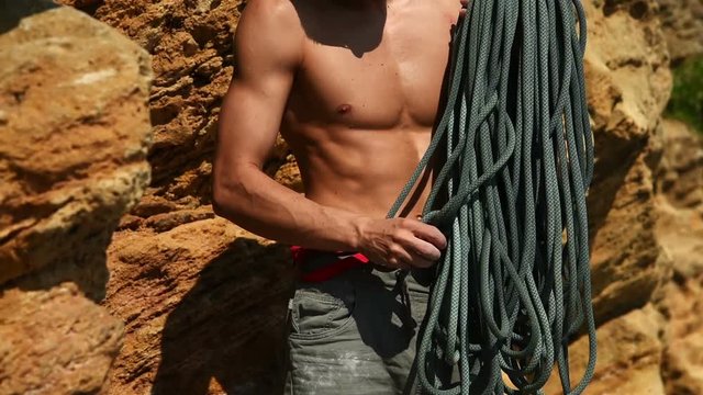 Muscular Climber Reels Off The Rope Standing At Foot Of Cliff