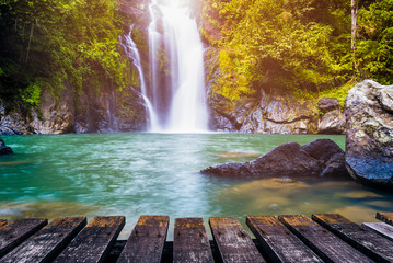Waterfall in deep forest and wood pier for background. Can be used for display or montage your products. - obrazy, fototapety, plakaty