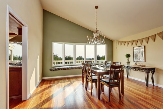 Elegant dining room with contrast olive wall and hardwood floor