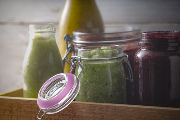 Jars with different smoothies  in the wooden box horizontal